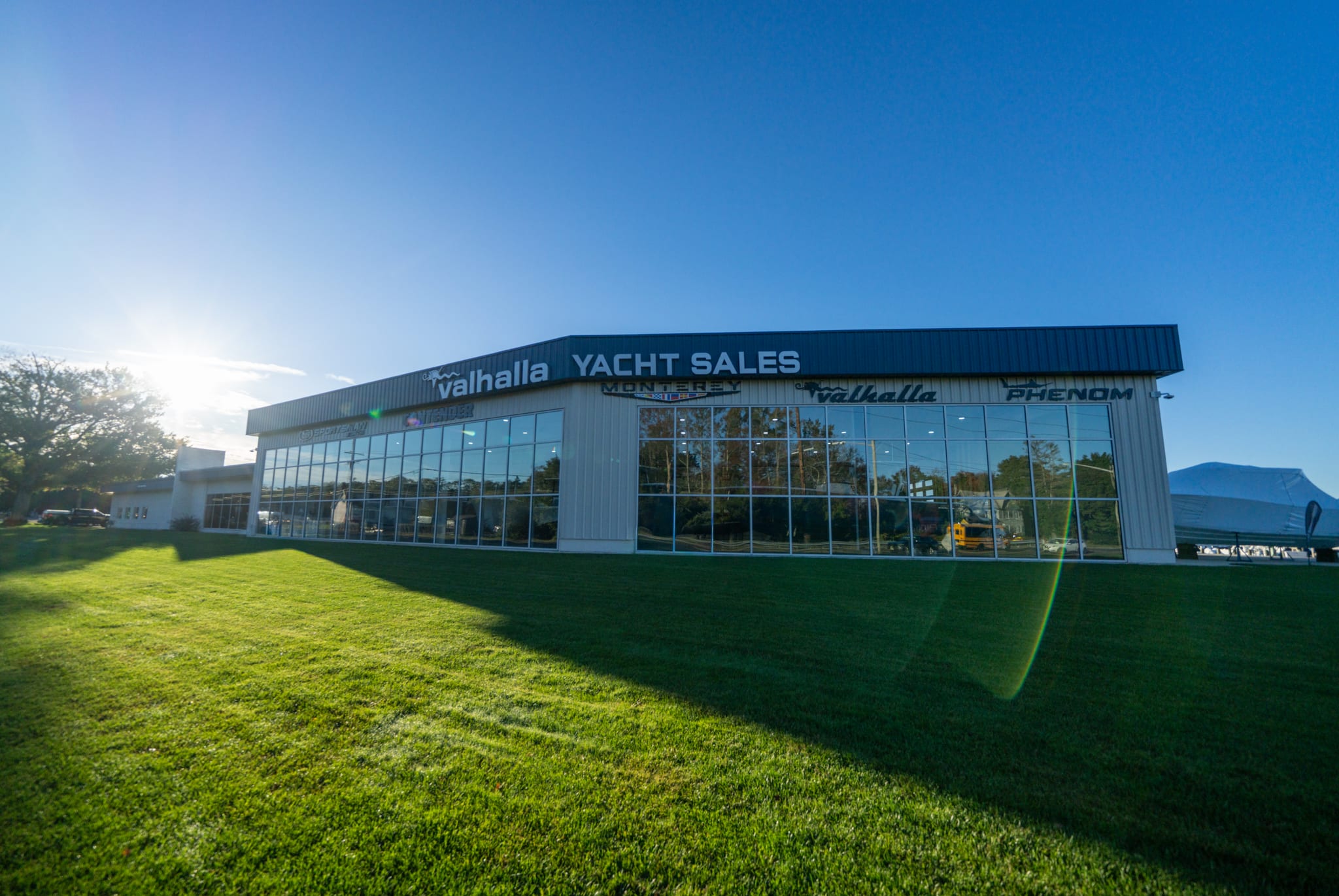 The New Gretna showroom on Route 9 on a sunny day, its glass storefront lined with Valhalla Yacht Sales and brand signage above a green lawn